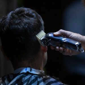 Barber using electric clipper for a precise haircut in a barber shop.